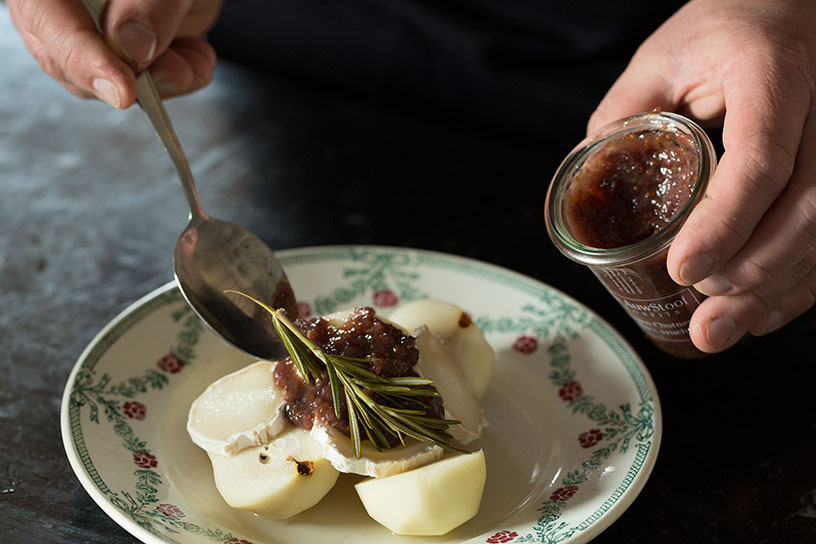 Stoofpeertjes op een bord met vijgenchutney en takjes rozemarijn 